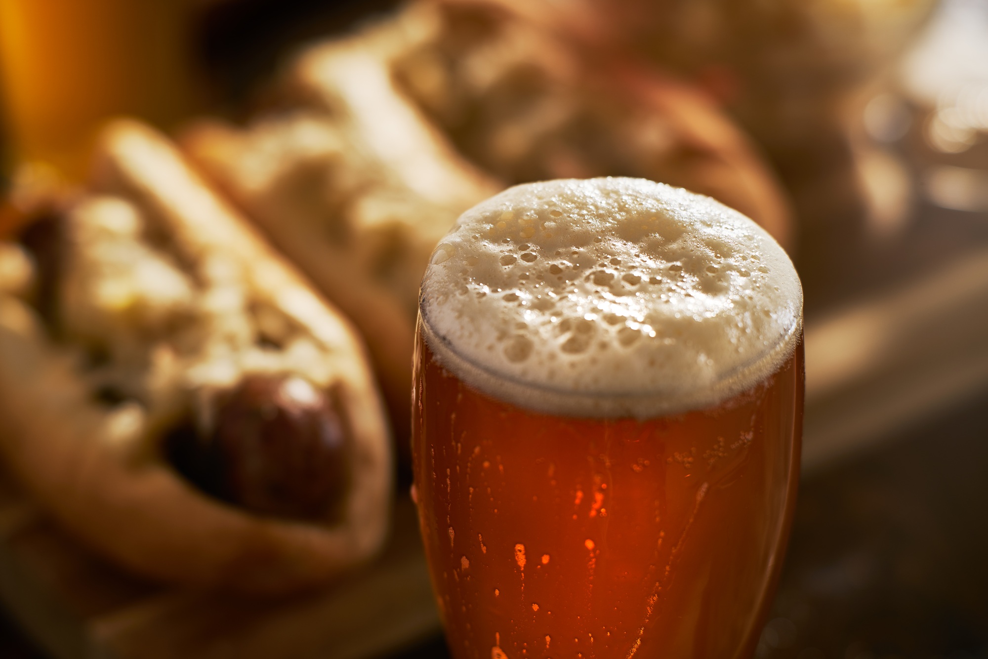 IPA beer in mug close up with foamy head served with bratwursts